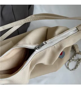 Dettaglio della cerniera e del decoro a cuore sulla borsa tote in tela beige