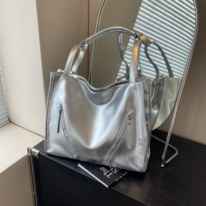 Detailed view of silver metallic tote bag with decorative zippers and sleek mirror finish