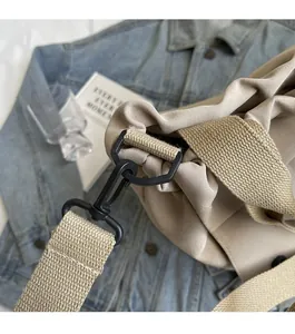 Détail du crochet en métal noir mat robuste sur un sac fourre-tout en toile beige