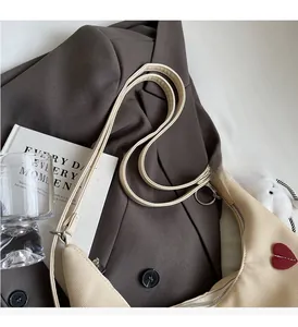 Dettaglio della borsa tote in tela bianco sporco con toppa a cuore rosso su un blazer