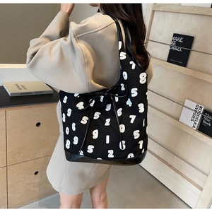 Detail of black tote bag featuring white number prints and side ribbon bow decoration