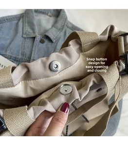 Gros plan du fermoir magnétique et de la poignée en sangle sur le sac cabas en toile beige