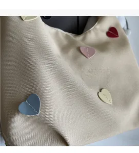 Dettaglio della trama in tela beige con toppe colorate a forma di cuore e cuciture