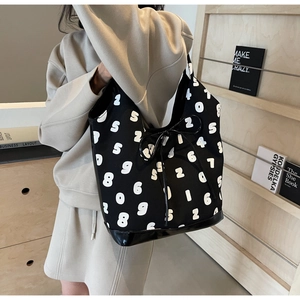 Detail view of large black canvas tote featuring white numeral prints and drawstring bow