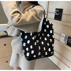 Detailed view of black canvas tote with white digit print and leather base