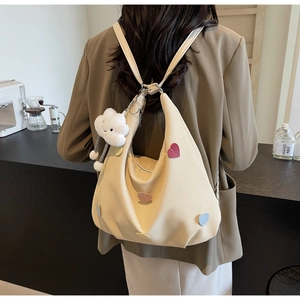 Donna che indossa una borsa a mezzaluna in tela beige con toppe a cuore e nuvola