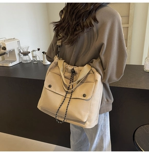 Détail du grand sac cabas en toile beige avec cordon de serrage et poche à bouton-pression