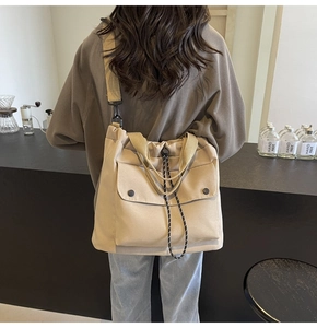 Détail du sac cabas en toile beige avec poche avant à rabat et fermeture à cordon noir
