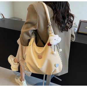Borsa tote in tela beige con toppe a cuore colorate e ciondolo a nuvola su modella
