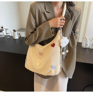 Borsa tote in tela beige con toppe a cuore colorate e ciondolo a nuvola in un ambiente bar
