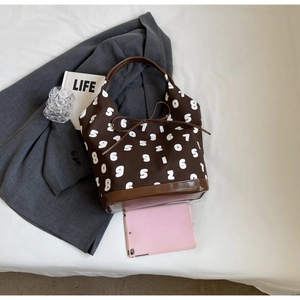 Macro detail of brown canvas hobo bag with white numeric print and faux leather trim