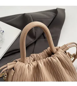 Détail de la poignée en cuir matelassé et fermeture à cordon sur un sac seau beige chic