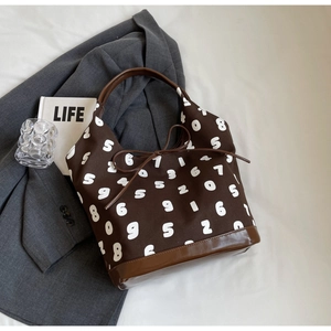 Detail of dark brown canvas tote with white numbers and bow knot on a grey blazer