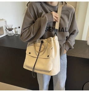 Détail du sac fourre-tout en toile blanc cassé avec doubles poches avant et cordon de serrage