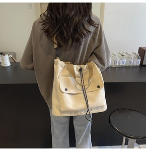 Détail du sac cabas en toile avec poche frontale à rabat et bandoulière réglable