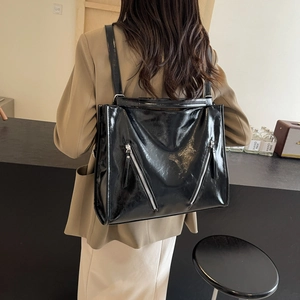 Glossy black convertible tote backpack with decorative silver zippers on a model back