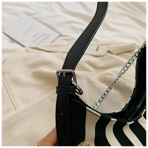 Dettaglio della borsa a righe in maglia con tracolla in pelle nera e fibbie argentate