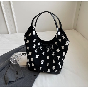 Detail of minimalist black tote bag with white numeric pattern and bow strap accent