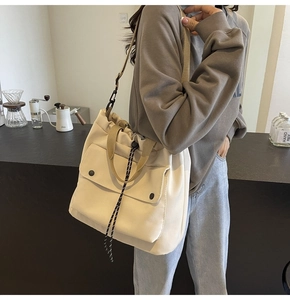 Détail du sac fourre-tout en toile crème avec poche frontale et bandoulière sur soi