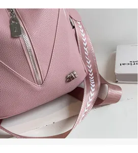 Close-up of pink litchi leather bag featuring silver hardware and patterned woven strap