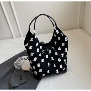 Detail of a large black tote bag with white number prints and leather handle contrast