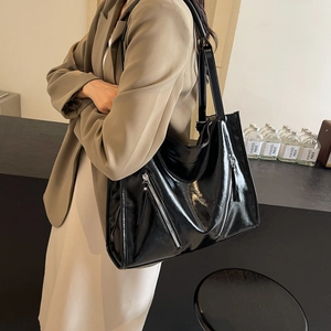 Chic black faux leather tote bag with decorative zipper and long straps for shoulder wear