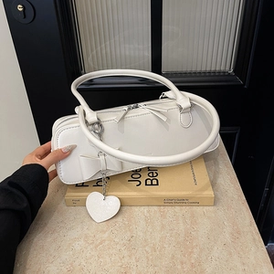 Détail du sac en similicuir blanc crème avec nœud décoratif et pendentif cœur