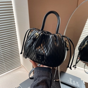 Détail du sac seau noir premium montrant la texture plissée et les boucles dorées
