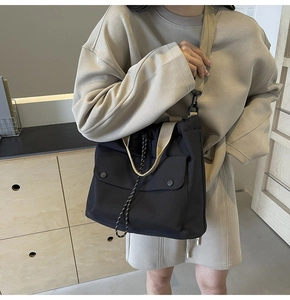 Détail du sac à bandoulière en toile noire à grande capacité et sangles beiges