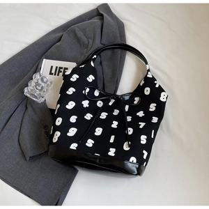 Detail of black and white tote bag with numeric print, bow accent, and leather base