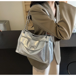 Detail of silver metallic tote bag featuring a bow buckle and stylish chain strap