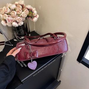 Détail du sac rouge foncé avec nœud en cuir texturé et pendentif en forme de cœur