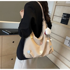 Dettaglio borsa tote beige con toppe a cuore, ciondolo a nuvola e catena moda