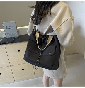 Détail du sac cabas en toile noire avec fermeture à cordon et bandoulière en kaki