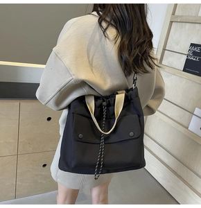 Détail du sac cabas en toile noire avec fermeture à cordon et poches à pression