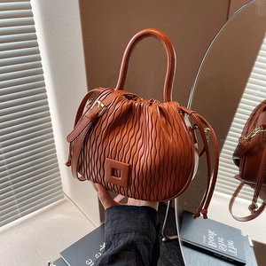 Détail du sac seau plissé orange montrant la texture ondulée et la boucle chic