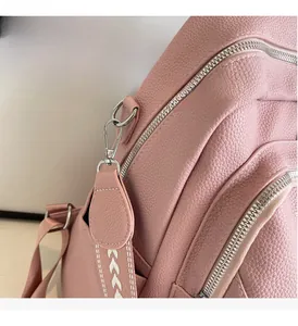 Close-up of pink lychee grain leather backpack with silver metal zippers and geometric straps
