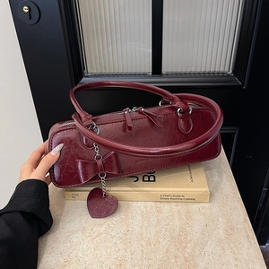 Détail du cuir plissé bordeaux avec nœud décoratif et pendentif en forme de cœur argenté
