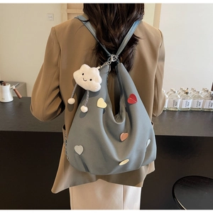 Borsa tote in tela grigio-blu con toppe a cuore e ciondolo a nuvola indossata dal modello