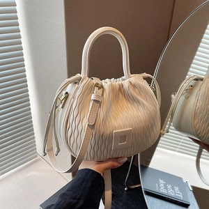 Détail du sac seau plissé blanc crème montrant la texture ondulée et la bandoulière réglable