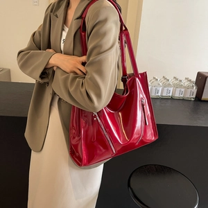 Detailed close-up of glossy red tote bag featuring stylish silver metal zippers