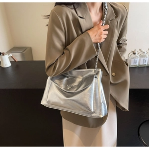 Silver chain tote bag with bow detail shown on a model in a minimal indoor setting