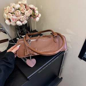 Détail d'un sac à main marron texturé avec décoration nœud et pendentif en cœur