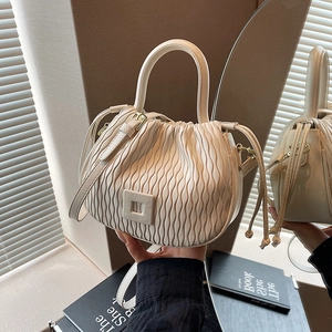 Détail du sac seau crème montrant le cuir plissé et l'anse ronde par reflet miroir