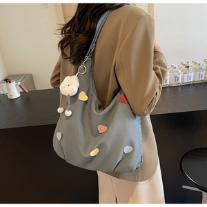 Dettaglio di una grande borsa hobo in tela blu con cuori colorati e un ciondolo a forma di coniglio