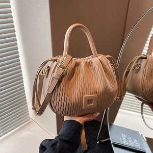 Détail du sac seau plissé beige montrant la texture ondulée et la poignée supérieure
