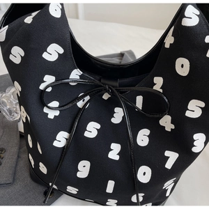 Detail of black canvas tote with white numbers print and elegant bow tie closure