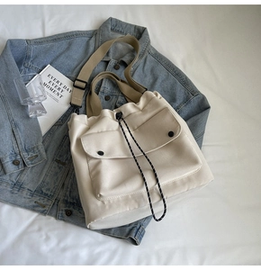 Détail du sac cabas en toile crème avec fermeture à cordon et bandoulière réglable