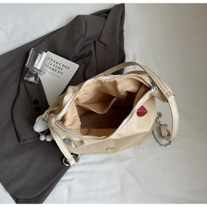 Dettaglio della borsa tote in tela beige con ricami a cuore e catena argentata