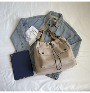 Détail du sac en toile beige avec fermeture à cordon et deux poches cargo